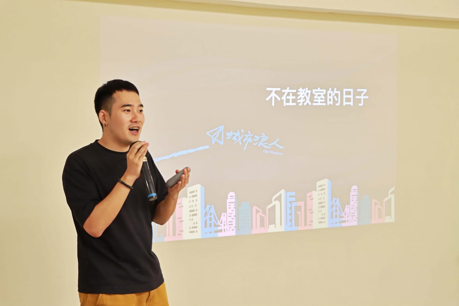 Corrie 拿著麥克風向現場分享,身後投影片是城市浪人的「不在教室的日子」
